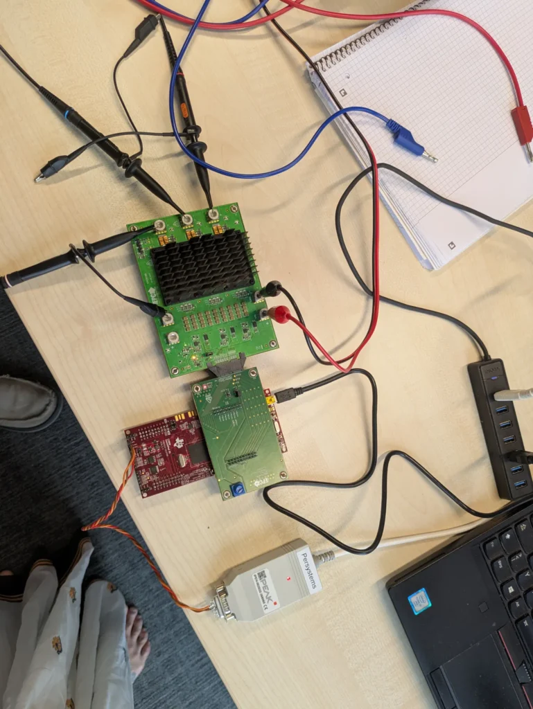 Inverter board at the test station with oscilloscope probes, development board and notes